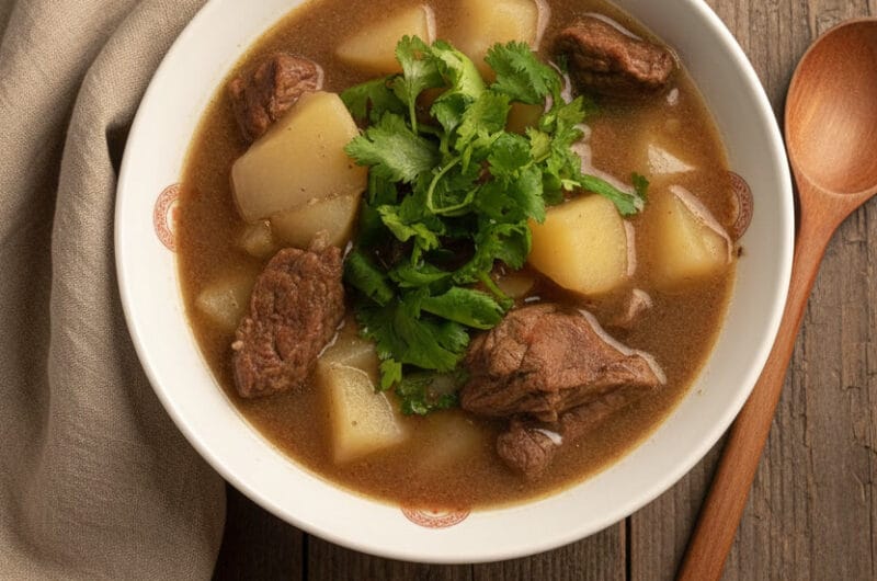 Beef and Potato Soup in a white bowl with chopped cilantro, served with crusty bread