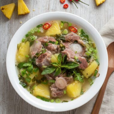 Bowl of Cambodian oxtail and pineapple soup with fresh herbs on top