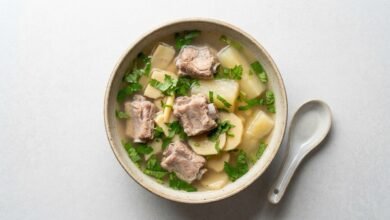 Overhead view of Cambodian bamboo shoots and yucca soup with pork ribs and saw leaf herb in a ceramic bowl.