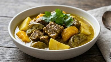 A bowl of Cambodian Beef Curry with Mango showing tender beef chunks, potato, Asian eggplant, and mango in a golden coconut broth.