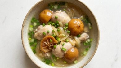 Overhead view of Cambodian chicken soup with preserved lemon and green onion in a bowl.