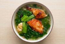 A bowl of Cambodian mustard green soup with roasted pork and chopped green onions.