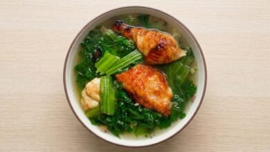 A bowl of Cambodian mustard green soup with roasted pork and chopped green onions.