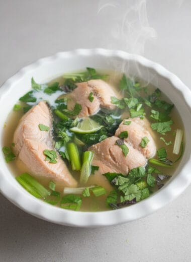 Cambodian salmon lime soup with fresh herbs served in a bowl