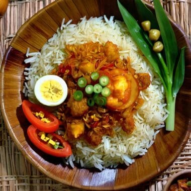 Cone-shaped Indonesian turmeric rice with side dishes on a banana leaf.