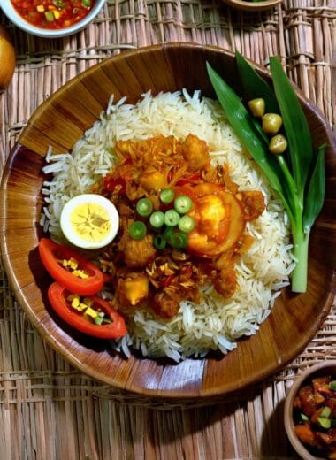 Cone-shaped Indonesian turmeric rice with side dishes on a banana leaf.