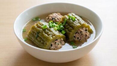 A bowl of Cambodian ground pork stuffed bitter melon soup with clear broth and green onion garnish