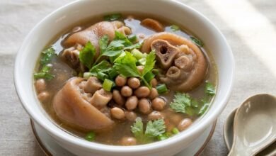 A bowl of Cambodian peanut soup with pork hocks, peanuts, and green onion garnish.
