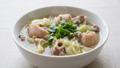 Overhead view of Cambodian pork hocks and cabbage soup in a bowl, garnished with cilantro and green onion.