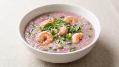 Overhead view of purple yam soup with shrimp in a bowl, garnished with green onion.