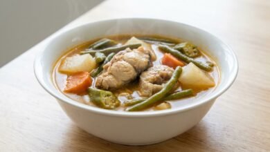 Overhead view of Cambodian vegetable fish stew with catfish, daikon, carrots, green beans, and okra in a bowl.