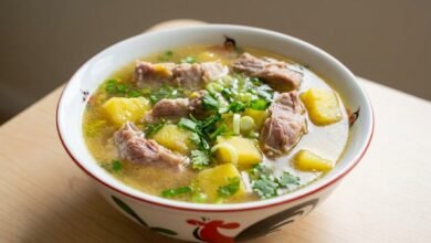 Overhead view of a bowl of Cambodian yellow yam soup with pork ribs and green onion.