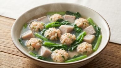 Overhead view of Cambodian yu choy with taro and shrimp ball soup in a bowl, showing shrimp balls, taro cubes, and green yu choy in clear broth.
