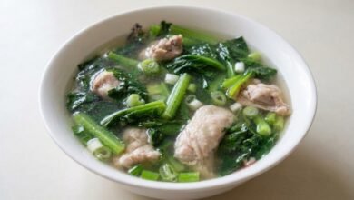 Overhead view of yuchoy with chicken soup in a bowl with green onion on top.