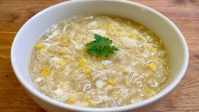 Overhead view of a bowl of Cambodian fish maw and crab soup with egg ribbons and green onions.
