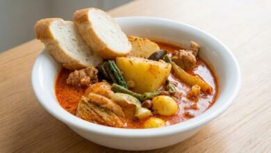 Overhead view of Khmer red chicken curry with bone-in chicken, snake beans, aubergine, and potatoes in a creamy coconut sauce.