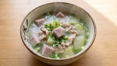 Overhead view of Cambodian pork with taro root soup in a bowl, topped with green onion and rice paddy herb.