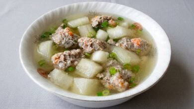 Overhead view of a bowl of Cambodian winter melon soup with pork and shrimp meatballs, garnished with green onion.