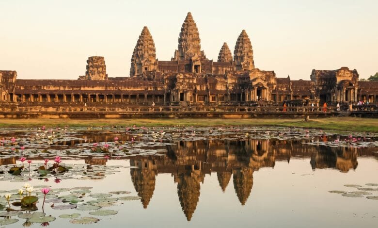 Angkor Wat temple at sunrise with its five towers reflected in the lotus pond