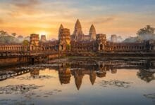 Angkor Wat temple complex at sunrise, with its five towers reflected in the moat