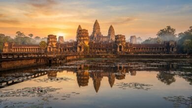 Angkor Wat temple complex at sunrise, with its five towers reflected in the moat