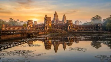 Angkor Wat temple complex at sunrise, with its five towers reflected in the moat