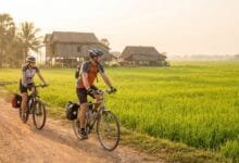 Bicycle on a rural road with rice paddies and traditional stilt houses in Battambang, Cambodia