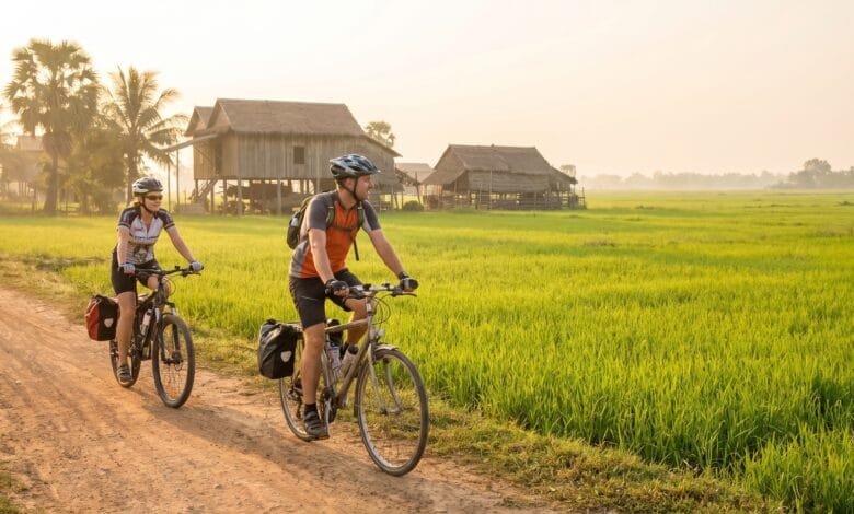 Bicycle on a rural road with rice paddies and traditional stilt houses in Battambang, Cambodia