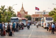 Travelers with luggage waiting near an immigration checkpoint at a Cambodia land border crossing