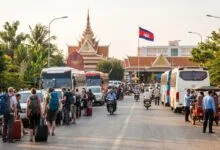 Travelers with luggage waiting near an immigration checkpoint at a Cambodia land border crossing