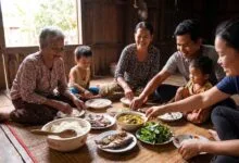 Cambodian family of three generations sharing a traditional meal with a central bowl of rice at a wooden dining table