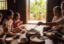 A Cambodian family sharing a traditional soup meal around a table with bowls of rice