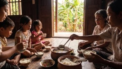 A Cambodian family sharing a traditional soup meal around a table with bowls of rice