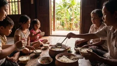 A Cambodian family sharing a traditional soup meal around a table with bowls of rice