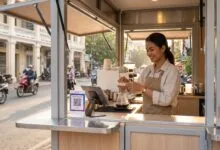 A young Cambodian woman entrepreneur prepares coffee at a modern kiosk on a Phnom Penh street