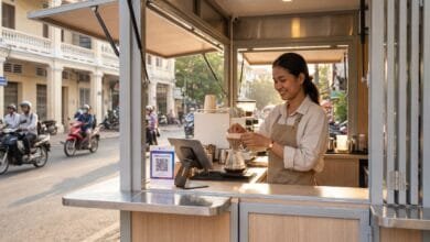 A young Cambodian woman entrepreneur prepares coffee at a modern kiosk on a Phnom Penh street