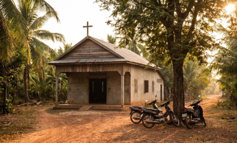 A small church building with a cross on the roof, surrounded by tropical vegetation in Cambodia
