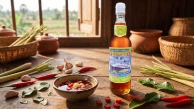 Traditional Cambodian fish sauce bottle and dipping bowl with chili and garlic on a wooden table