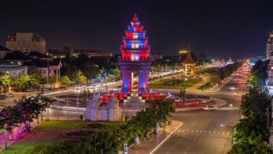 Independence Monument in Phnom Penh illuminated at dusk with red, blue, and white lights