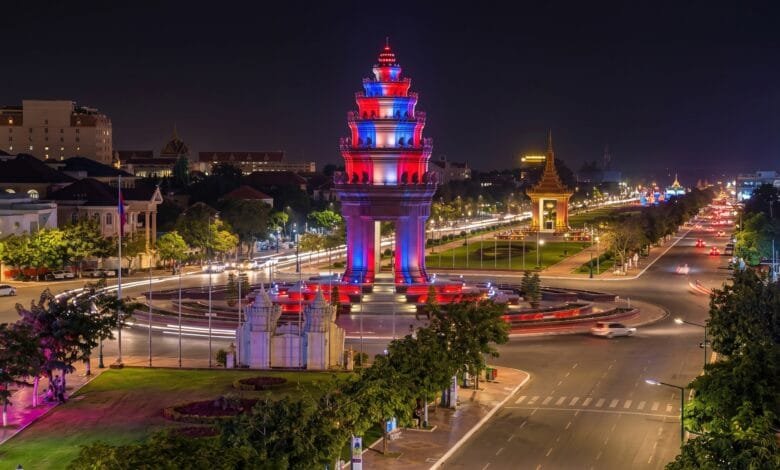 Independence Monument in Phnom Penh illuminated at dusk with red, blue, and white lights