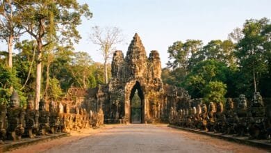 The South Gate of Angkor Thom with massive stone face towers and a causeway lined with god and demon statues.