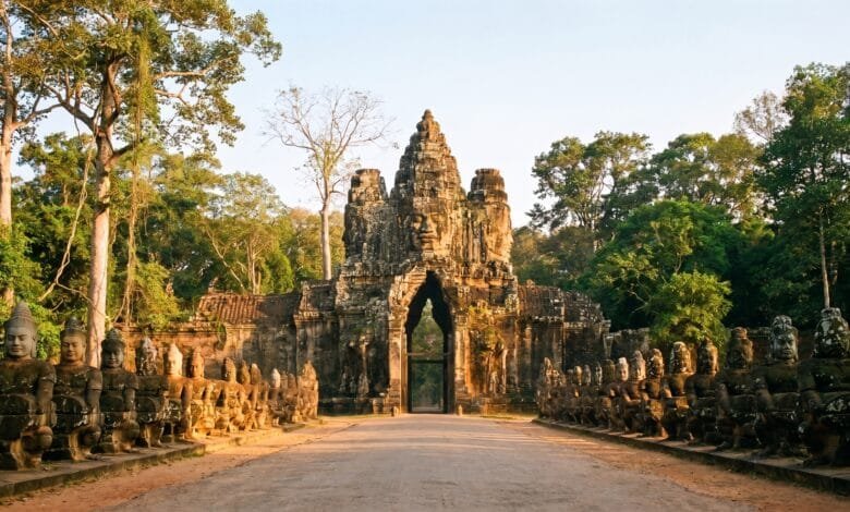 The South Gate of Angkor Thom with massive stone face towers and a causeway lined with god and demon statues.