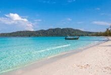Saracen Bay on Koh Rong Sanloem, Cambodia, showing a curved white sand beach with calm turquoise water and jungle-covered hills