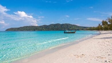 Saracen Bay on Koh Rong Sanloem, Cambodia, showing a curved white sand beach with calm turquoise water and jungle-covered hills