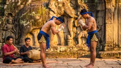 Two Kun Lbokator martial artists in traditional blue krama sashes performing at Angkor Archaeological Park in Cambodia
