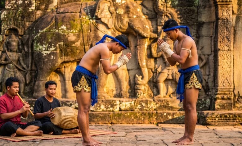 Two Kun Lbokator martial artists in traditional blue krama sashes performing at Angkor Archaeological Park in Cambodia