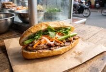 Cambodian nom pang baguette sandwich filled with grilled pork, pickled vegetables, and herbs at a street food stall