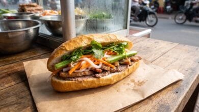 Cambodian nom pang baguette sandwich filled with grilled pork, pickled vegetables, and herbs at a street food stall
