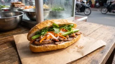 Cambodian nom pang baguette sandwich filled with grilled pork, pickled vegetables, and herbs at a street food stall