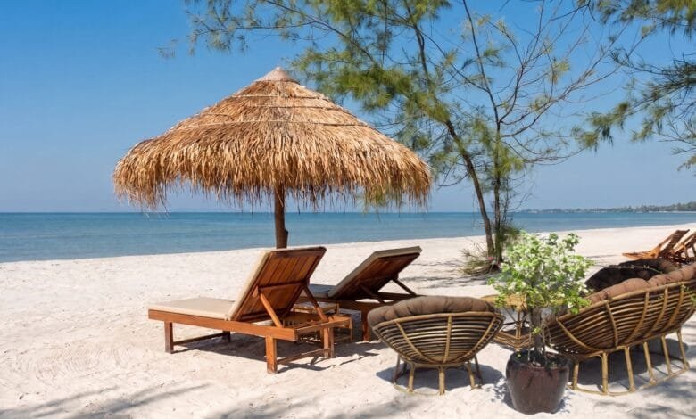 Pale sand and calm water at Otres Beach in Sihanoukville, Cambodia, with casuarina trees along the shoreline.